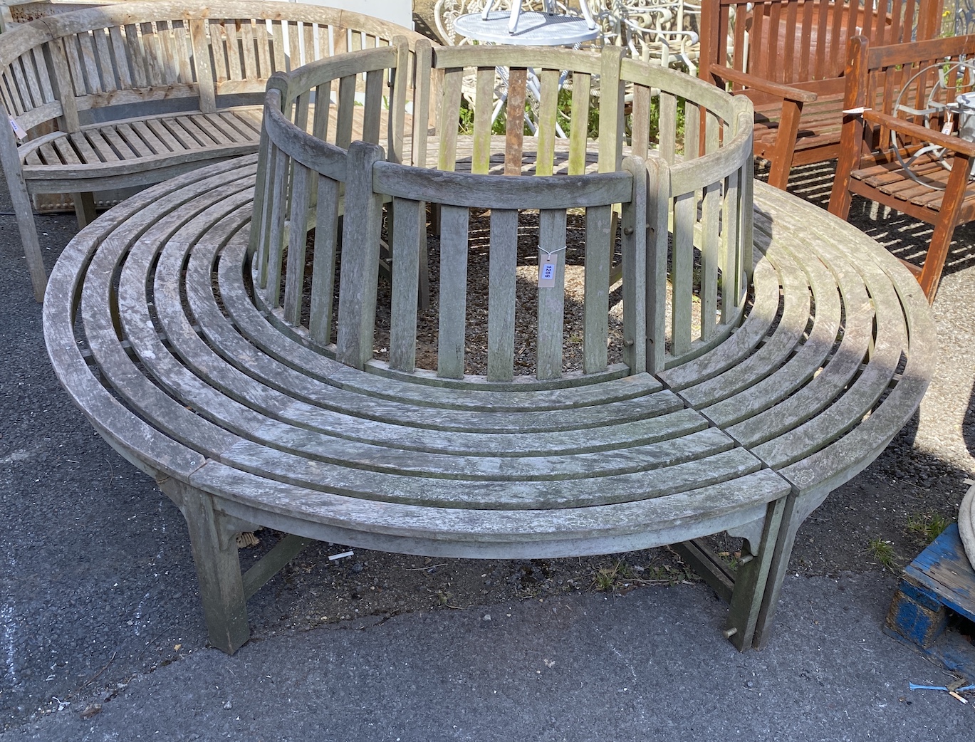 A weathered teak circular two section tree seat, diameter 220cm, inner diameter approximately 110cm, height 94cm